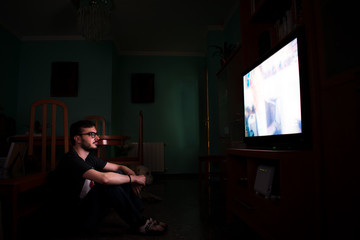 Fototapeta na wymiar Man watching tv and zapping sitting on the floor at home.
