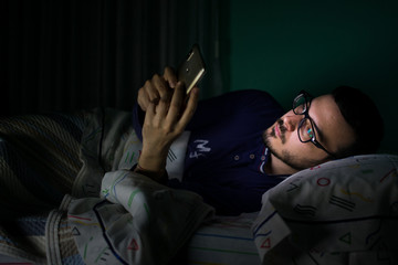 Obraz premium Man looking his mobile phone in the bed at night