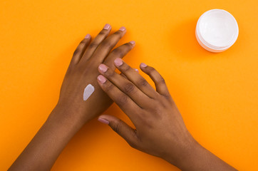 African american woman applying cosmetic hand cream on skin