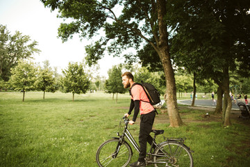 Obraz premium A young and handsome man riding a bicycle in the park