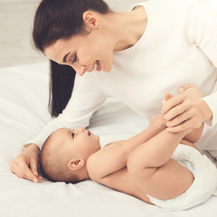 Mother playing with her baby in bedroom.