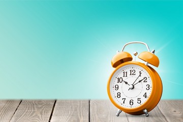 Orange retro alarm clock on wooden table on wall background