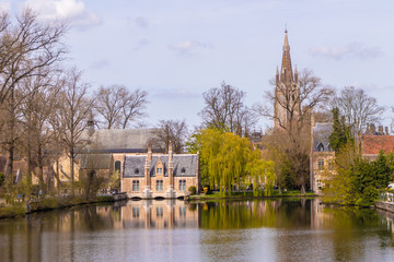 Fototapeta na wymiar Bruges, Belgium - APRIL 05, 2019: Minnewater lake and medieval castle in Bruges