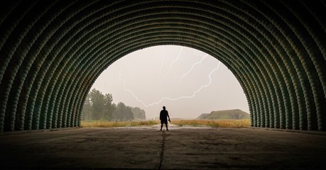 Silhouette of man standing in the hangar and watching lightning