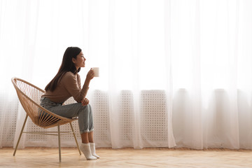 Young Girl Sitting In Modern Chair, Enjoying Coffee