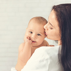 Mother kiss child, baby rests on mom shoulder
