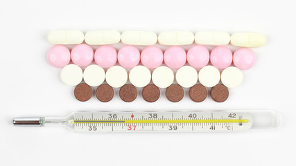 thermometer and medical pills on white background