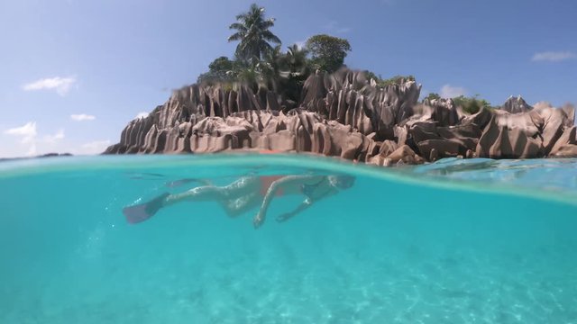 Split view of female apnea underwater and paradisiacal landscape of St. Pierre Island coral reef in Seychelles. Snorkeling woman exploring sealife of Indian Ocean, under and above water photography.