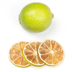 fresh green lemon and pieces of dried lemon on white background