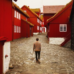 man in front of thatched houses on cobblestone street