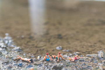 Miniature people wearing swimsuit relaxing on the beach , Summer concept