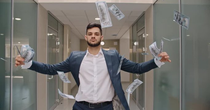 Caucasian man with arrogant face is standing in office hall throwing money in air, celebrating his success - way to success concept 4k