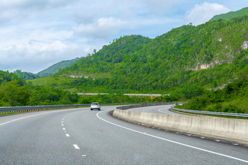 Two lane street/ double lane road on dual carriageway highway through scenic countryside mountain landscape. Vehicles drive on left hand side of the road. Saint Ann/St Ann, Jamaica.