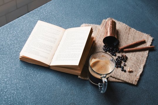 Table top photo of coffee cups and ingredients with a book ready for work or study. Hipster lifestyle, travel inspiration for cafe shop.
