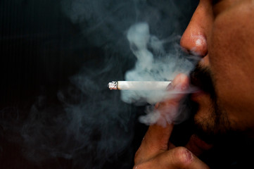 Close up young man smoking a cigarette
