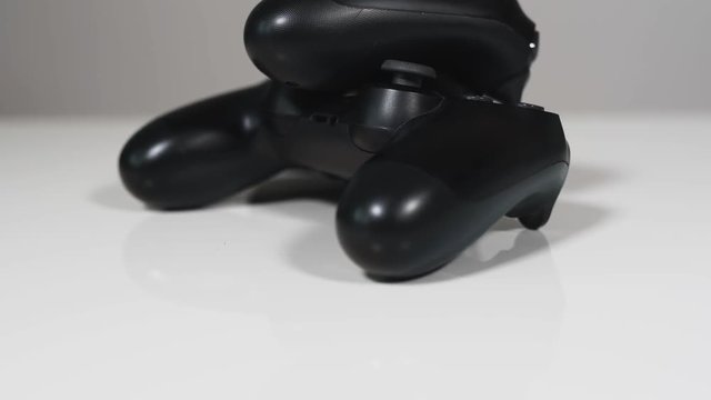 Closeup of two handheld controllers from a gaming system. Tilting from buttom to the top. With a white background.