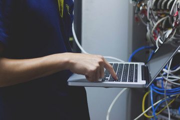 Technician administrator typing on his notebook in data center room