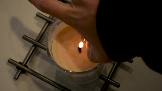 Closeup, male burns hand causing pain reflex with lighter trying to light wax decorative candle.