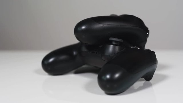 Closeup of two handheld controllers from a gaming system. Tilting and panning from top left to buttom right. With a white background.