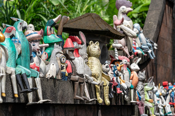 Old wooden souvenirs toys on the stone fence near the doll shop in Ubud, Bali island, Indonesia. Closeup