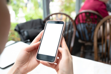 Mockup image of hand holding white mobile phone with blank screen with woman  modern cafe.
