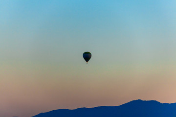 Silhouette of Colorful  hot air balloon is flying  over mountain  in blue sky at sunset 