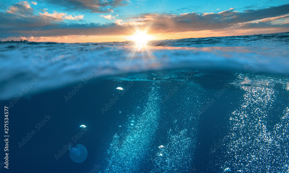 Wall mural water background, beautiful tropical sea, underwater view with sunset on skyline