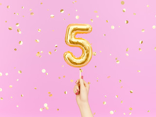 Five year birthday. Female hand holding Number 5 foil balloon.  Five-year anniversary background....