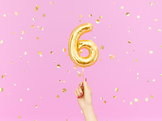 Six year birthday. Female hand holding Number 6 foil balloon. Six-year anniversary background. 3d...