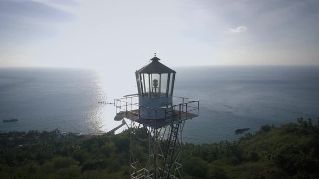 Aerial shot of an old light house steel tower in a small island, backed with sunset, surrounded by blue ocean in the afternoon. Shot at Marore Island, North Sulawesi, Indonesia.