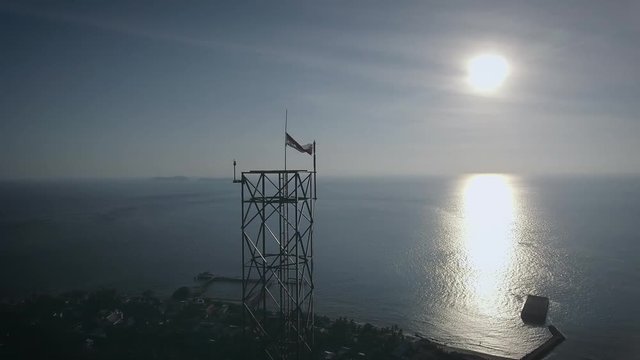 Aerial shot of an BTS Base Transceiver Station steel tower in a small island, backed with sunset, surrounded by blue ocean in the afternoon. Shot at Marore Island, North Sulawesi, Indonesia.