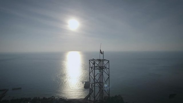 Aerial shot of an BTS Base Transceiver Station steel tower in a small island, backed with sunset, surrounded by blue ocean in the afternoon. Shot at Marore Island, North Sulawesi, Indonesia.