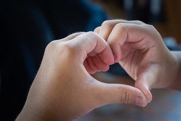 Close-up photo of hands a child making fingers showing as a heart symbol to say that I love you. The heart shape tells the love feel romantic that is given to each other. Valentine's day.