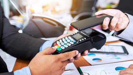 Business man payment by NFC technology with credit card reader machine and smartphone app.