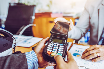 Business man payment by NFC technology with credit card reader machine and smartphone app.