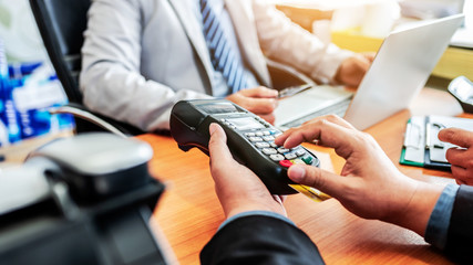 Group of business holding credit card with NFC payment system in modern office.