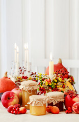 Glass jars with honey among autumn floral decorations.