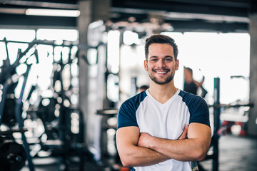Fototapeta na wymiar Portrait of a smiling young man in sportswear in the gym, looking at camera.