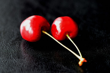 Two ripe berries of a sweet cherry on a dark background close up