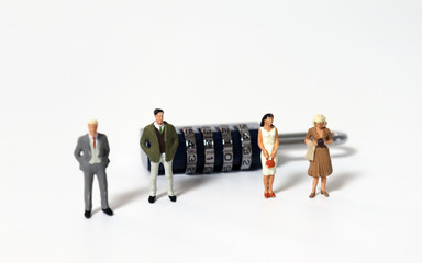 Miniature people standing in front of a combination lock.