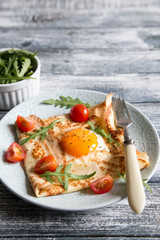 Crepes with eggs, cheese, arugula leaves and tomatoes. Galette complete. Traditional dish galette sarrasin.