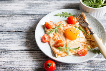 Crepes with eggs, cheese, arugula leaves and tomatoes. Galette complete. Traditional dish galette sarrasin.