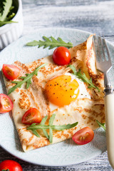 Crepes with eggs, cheese, arugula leaves and tomatoes. Galette complete. Traditional dish galette sarrasin.