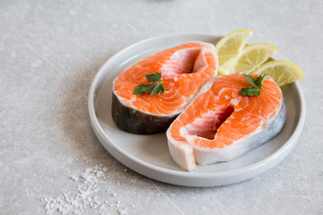 fresh fish. fresh salmon steaks with lemon, spices and salt in a light plate