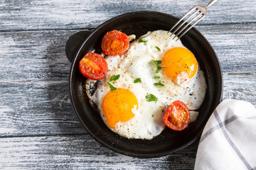 Naklejka na ściany i meble Fried egg. Close up view of the fried egg on a frying pan with cherry tomatoes and parsley