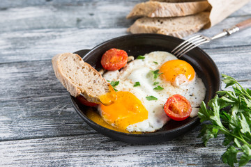 Fried egg. Close up view of the fried egg on a frying pan with cherry tomatoes and parsley