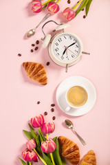 Obraz na płótnie Canvas Morning coffee, croissants, alarm clock and a pink tulips. Flat lay