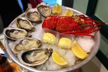 Large dish with fresh seafood, oysters with lobster with lemon and sauce on ice