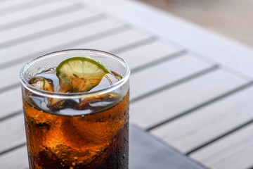 glass of cola with ice and lemon on table 