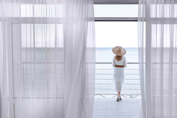 A woman enjoys the view of the sea with a beautiful view from the terrace in the early summer morning.